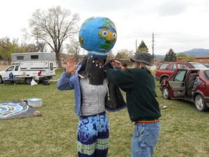 Love-In-Action member, Rick Brown, dressing a volunteer in his hand built Earth Puppet head costume before the Community Parade during the Global Climate Convergence in Taos, NM